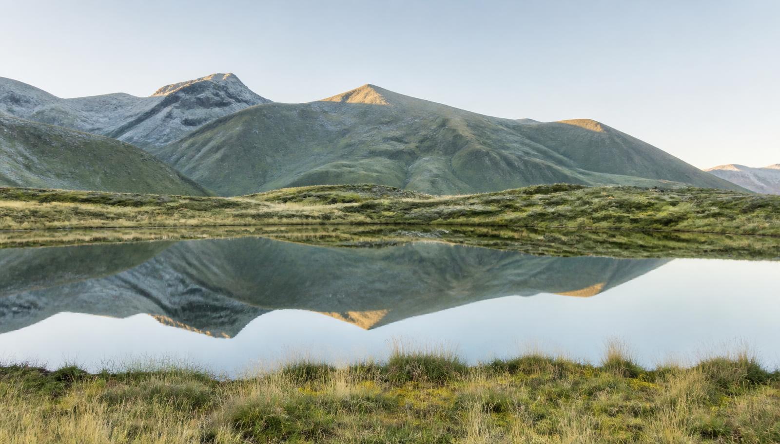 Lac de haute montagne andine reflétant les reliefs au lever du jour